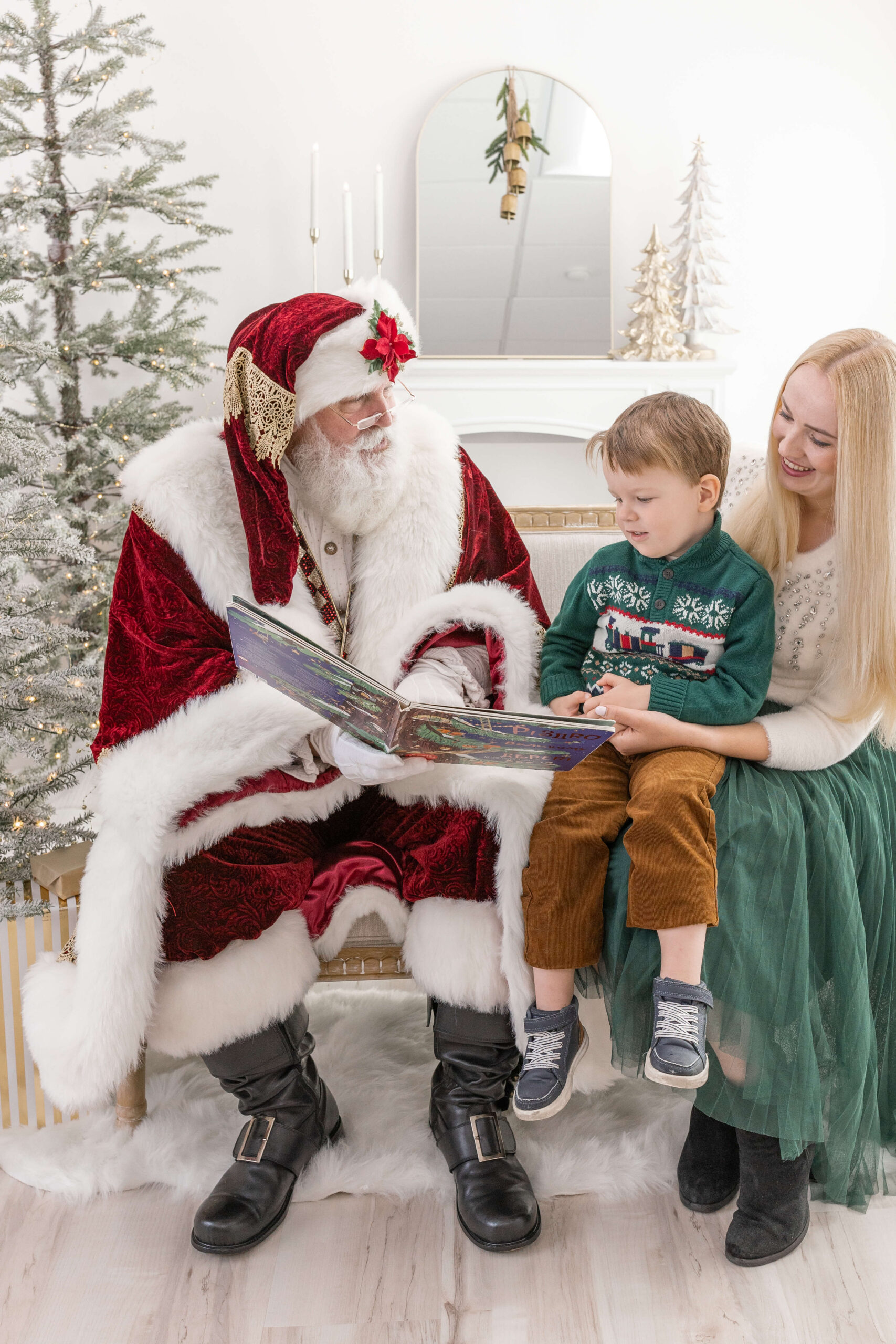 A mom and child on a couch reading a book with Santa