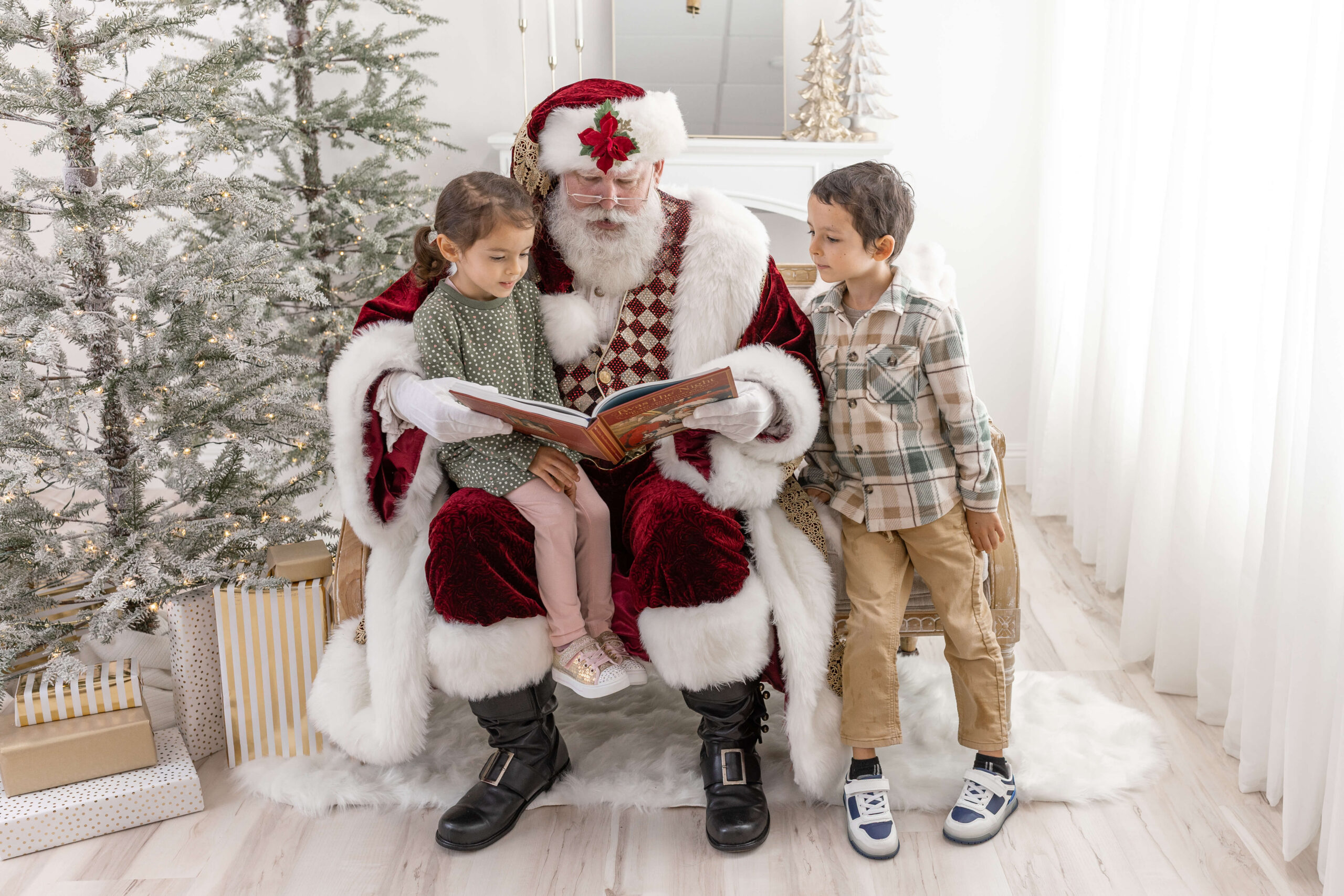 2 kids reading a book on a couch with Santa